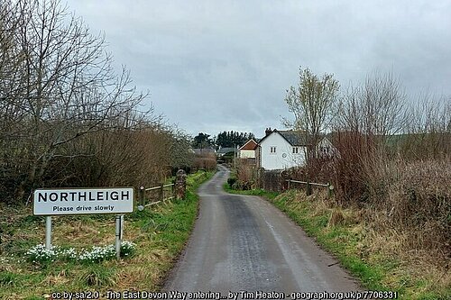 A road entering the village of Northleigh with a sign reading "Northleigh" on the left