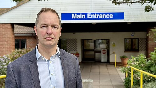 Seaton Hospital Main Entrance Jacket Richard Foord standing in front of the entrance to Seaton Hospital