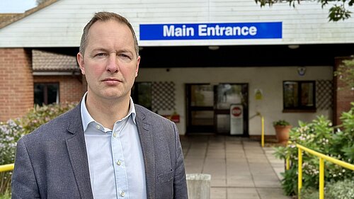 Seaton Hospital Main Entrance Jacket Richard Foord standing in front of the entrance to Seaton Hospital
