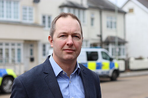 Richard Foord MP standing in front of a police van