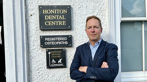 Honiton Dental Centre Richard Foord standing in frnt of the sign for Honiton Dental Centre