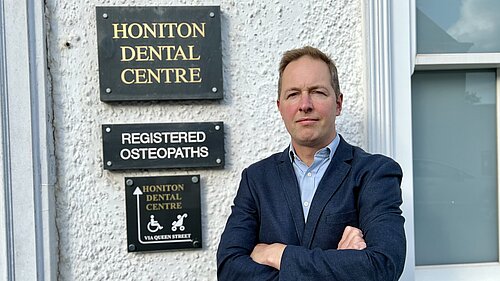 Honiton Dental Centre Richard Foord standing in frnt of the sign for Honiton Dental Centre
