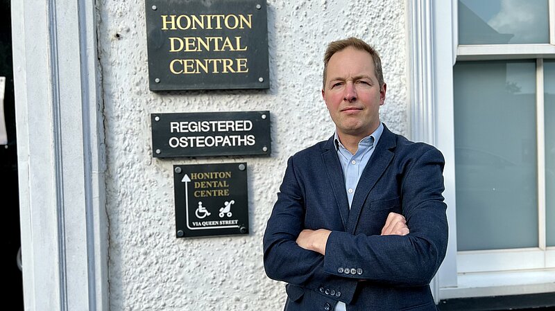 Richard Foord standing in frnt of the sign for Honiton Dental Centre