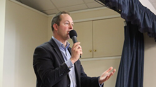 Richard Foord on a stage giving a talk while holding a microphone