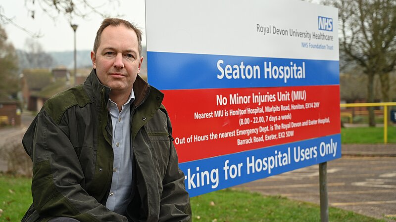 Richard Foord next to the sign for Seaton Hospital