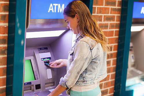 Stock image of a person standing at an ATM