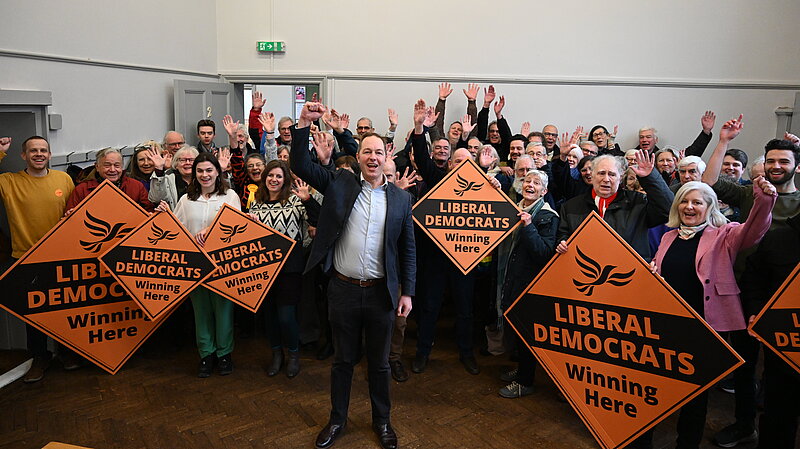 Richard Foord standing in front of a group of supporters holding "Liberal Democrat" posters