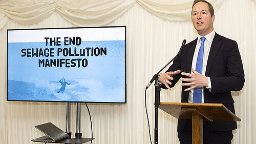 Sewage Pollution Manifesto Richard Foord standing next to a screen reading "The End Sewage Pollution Manifesto"