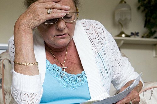 Woman looking concerned while reading a piece of paper