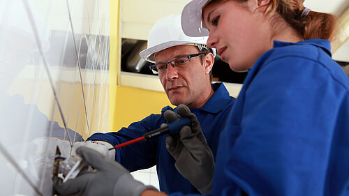 An electrician teaching an apprentice.