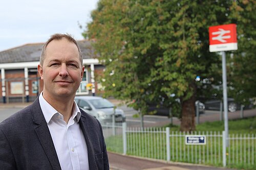 Richard Foord MP standing in front of a railway sign